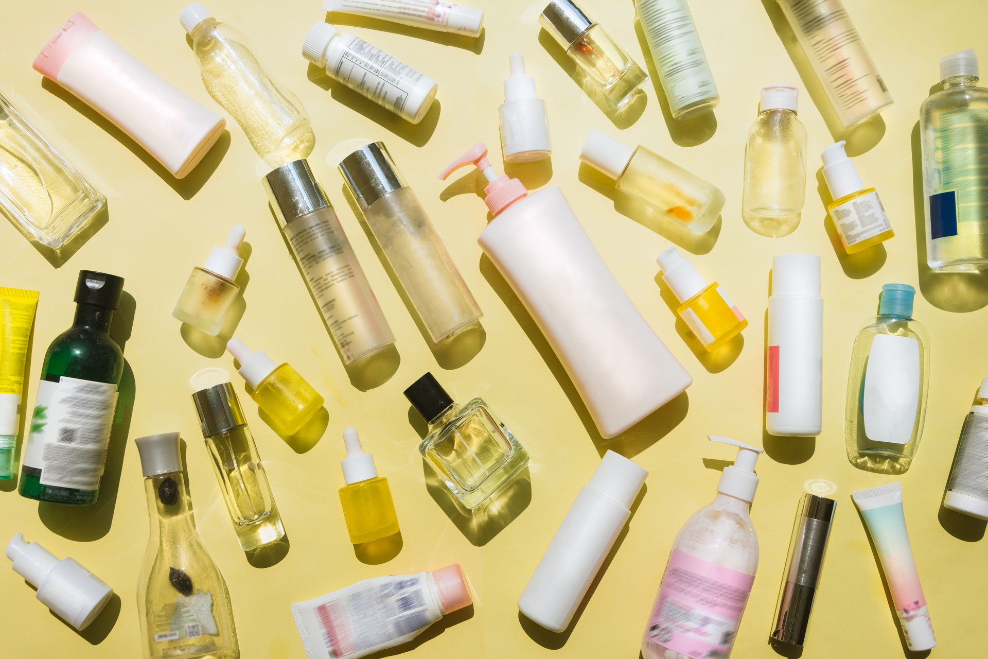 Beauty products, cosmetics products, perfume products, body care products, baby care products, and essential oil bottles on yellow background, all is empty bottles for being recycled