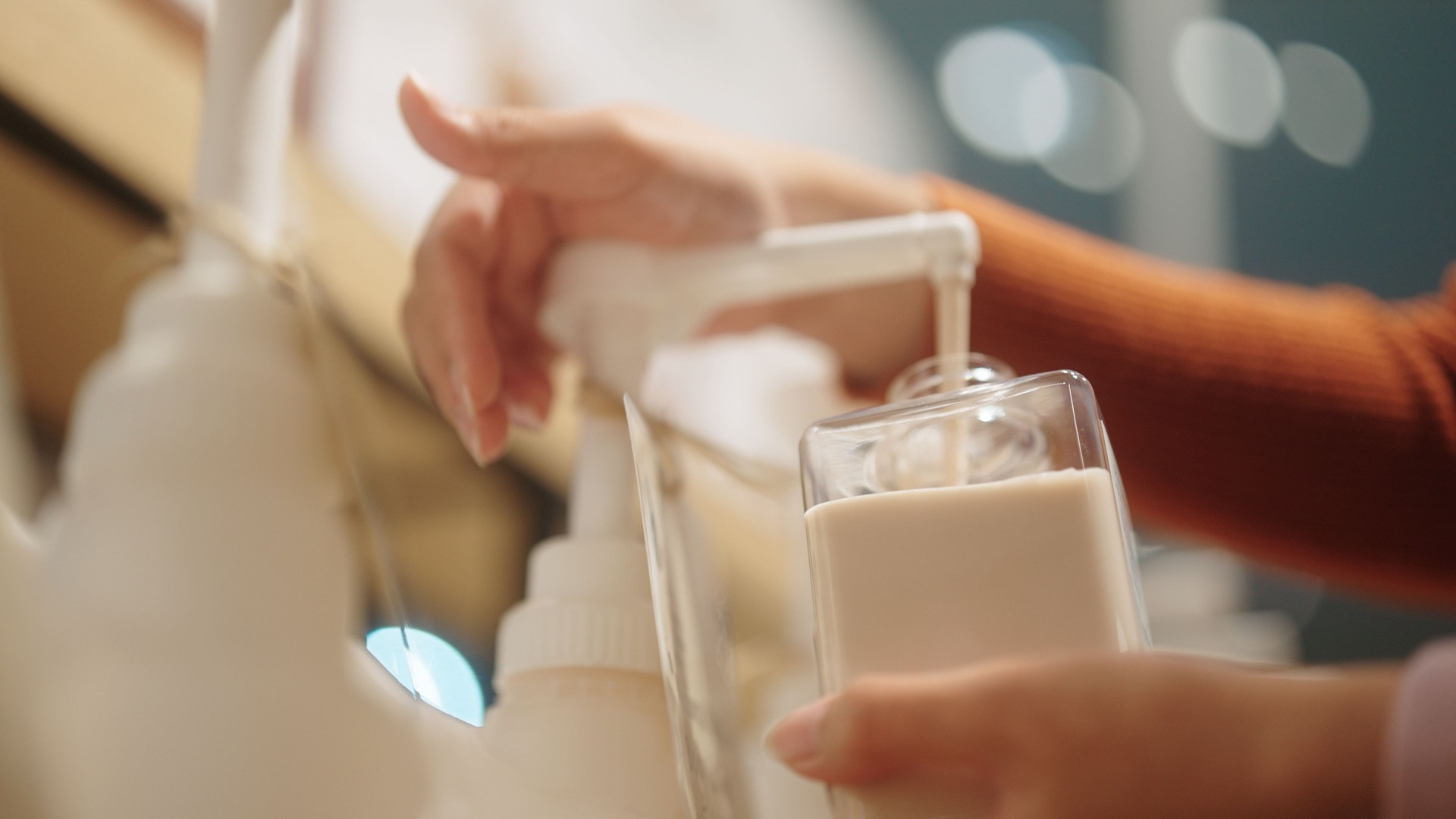 Woman refilling skin cream at sustain shop.